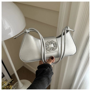 Close-up of silver shoulder bag featuring a sparkling crystal buckle and knotted strap