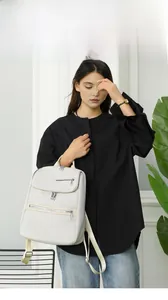 Lifestyle shot of woman wearing cream oxford backpack in a minimalist indoor setting