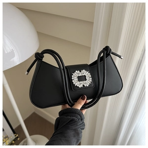 Detail of black crescent shoulder bag featuring a sparkling crystal buckle and knotted strap