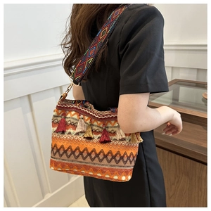 Detail of hand-woven bucket bag featuring ethnic geometric patterns and colorful tassels