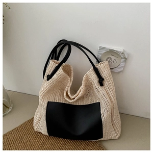 Detail of a straw tote bag with black faux leather pocket and long double handles