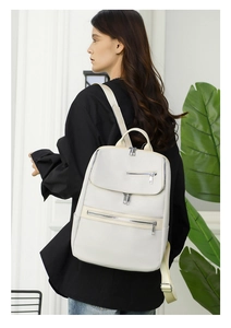 Close-up of adjustable fabric straps and silver metal zippers on the beige backpack