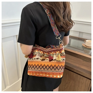 Detail of colorful woven straw bucket bag with tassels and ethnic style shoulder strap
