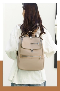 Rear view of minimalist khaki Oxford cloth backpack with leather texture and metal zippers