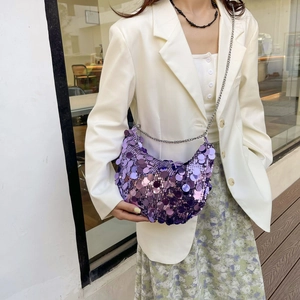 Elegant purple sequined crescent bag with silver chain strap worn by a model in outdoor