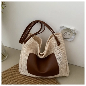 Close-up of beige straw woven tote with brown leather pocket and magnetic metal clasp