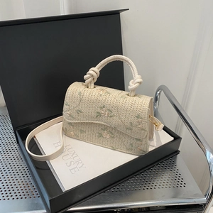 Chic woven straw crossbody bag with floral embroidery and a unique knotted handle