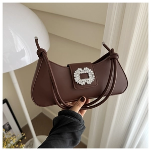 Detail of dark brown baguette bag with shimmering rhinestone buckle and elegant strap knot