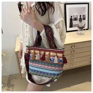 Close-up of ethnic straw bucket bag with colorful geometric weaving and tassel charms