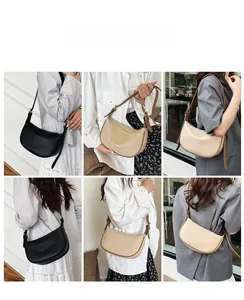 Model showing minimalist half-moon crossbody bag in black and cream leather with gold hardware