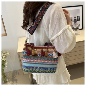 Close-up of ethnic straw bucket bag showing colorful woven patterns and tassel details