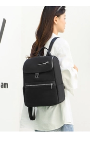 Side view of a casual black Oxford fabric backpack worn by a model in a white studio
