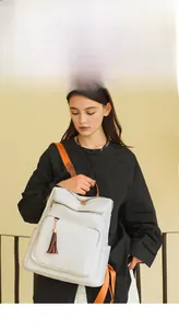 Detail of white lychee leather backpack with brown tassel and bright orange straps