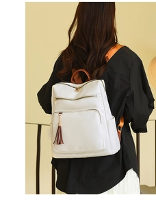 White faux leather backpack with leaf stitching and brown tassel shown on model