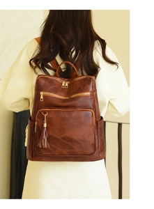 Detail of vintage brown leather backpack with leaf pattern stitching and fringe zipper