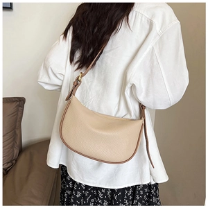Detail of beige pebbled leather crescent bag with contrasting brown shoulder strap trim