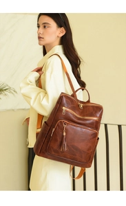 Side view of brown vintage leather backpack with leaf texture and fringe on female model