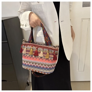 Detail of colorful bohemian straw bucket bag showing complex woven geometric patterns and fringe