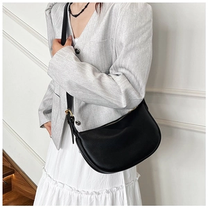 Detail of black lychee grain leather crescent bag showing texture and adjustable strap