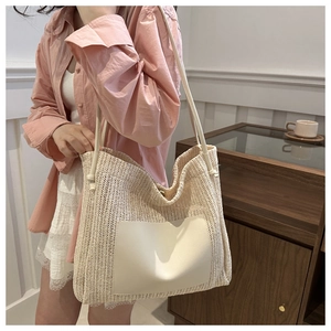 Detail of hand-woven straw tote bag with creamy leather pocket and slim shoulder straps