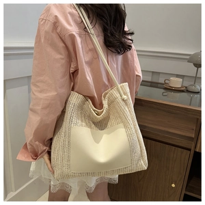 Detail of hand-woven beige tote bag featuring a leather patch pocket and long shoulder straps