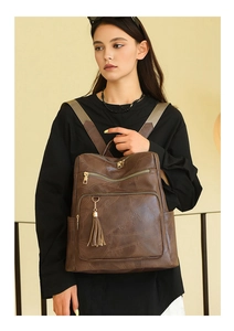 Detail of vintage brown leather backpack featuring patchwork texture and metal zippers