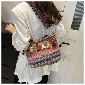 Detail of bohemian straw bucket bag with colorful tassels and ethnic woven strap on model