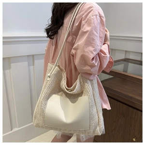 Straw tote bag in cream white with leather pocket worn by a model in a warm setting