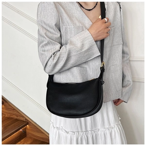 Detail of black crescent leather shoulder bag with fine lychee texture and gold hardware