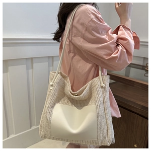Detail view of woven straw tote bag featuring white leather pocket and metal magnetic buckle