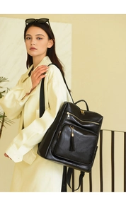 Detail of black faux leather backpack with pebble texture and gold zipper tassel accents