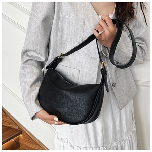 Model wearing black pebble leather crescent shoulder bag with golden hardware and strap