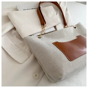 Details der beigen Canvas-Tasche mit brauner Ledertasche und goldener Kettenriemen