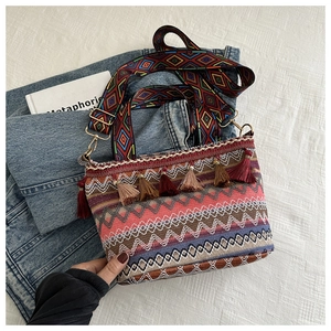 Detail of bohemian bucket bag with colorful woven patterns, tassels and wide shoulder strap