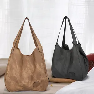 Close-up of matte leather tote bags in brown and black with embossed rectangular logo