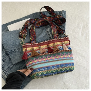 Detailed macro view of ethnic woven bucket bag featuring colorful tassels and patterned strap