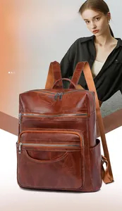Detail of vintage brown PU leather backpack featuring embossed leaf pattern and zip pockets