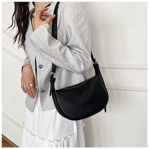 Detail of minimalist black pebble leather crescent bag with elegant gold zipper and hardware