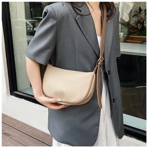 Chic cream dumpling bag with brown leather straps shown on a model in urban setting