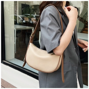Detail of cream pebbled leather crescent bag with brown trim and gold zipper hardware