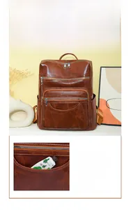 Detail shot of a brown vintage leather backpack featuring a half-moon shaped zipper pocket