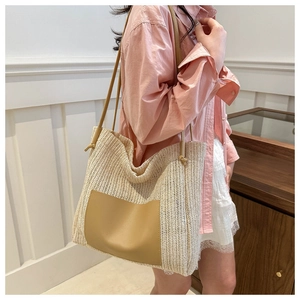 Detail of handwoven straw tote bag with faux leather pocket and slim shoulder straps