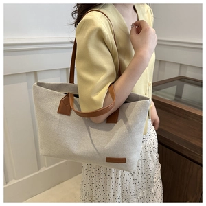 Detail of the high-quality canvas fabric texture and brown leather straps on the tote bag