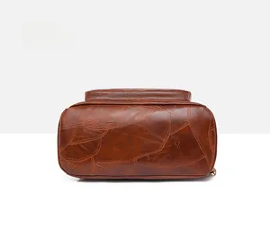 Detail shot of the bottom stitching and vintage brown leather texture of the travel backpack