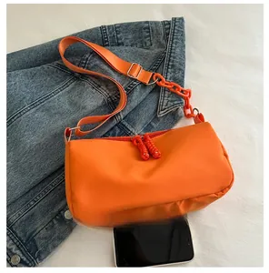 Detail of orange nylon crossbody bag with double zippers and chunky chain decoration