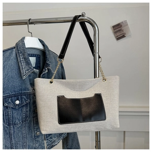 Detail der Canvas-Einkaufstasche mit schwarzer Ledertasche und Metallkettenriemen