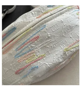 Détail du tissu blanc gaufré avec coutures ondulées colorées et motif monogramme chic