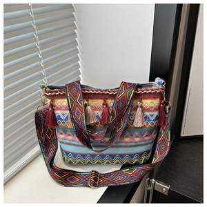 Close-up of bohemian woven bucket bag with colorful geometric patterns and red tassels
