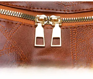 Close-up of premium brown litchi grain leather texture and smooth dual golden metal zippers