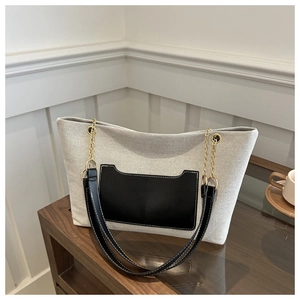 Detailaufnahme einer großen beige Nylon-Tragetasche mit schwarzer Ledertasche und Goldkette